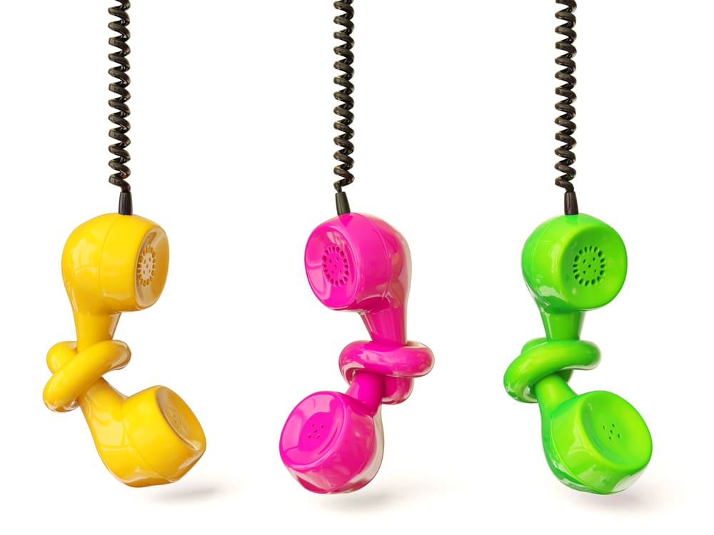 Drei bunte Telefonhörer in Gelb, Pink und Grün – Kontakt TILA DIGITAL